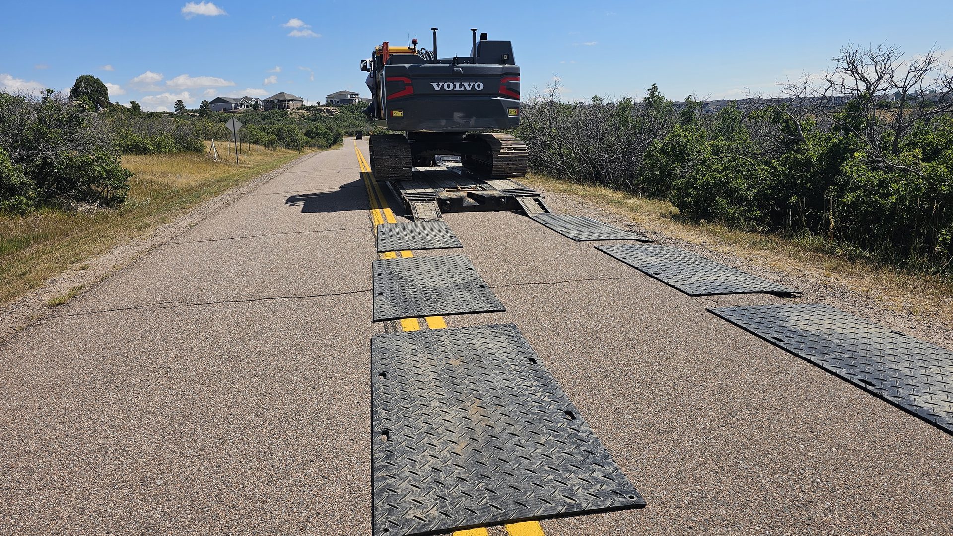 Excavator crossing asphalt on HDPE ground protection mats