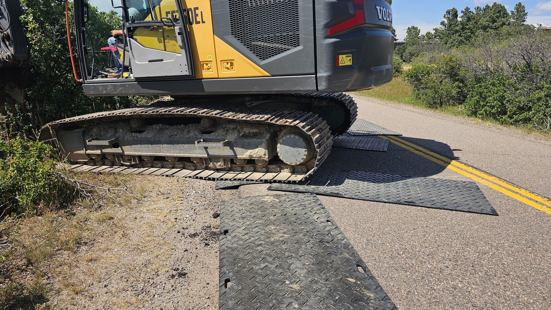 Excavator tracks on black HDPE mats protecting asphalt